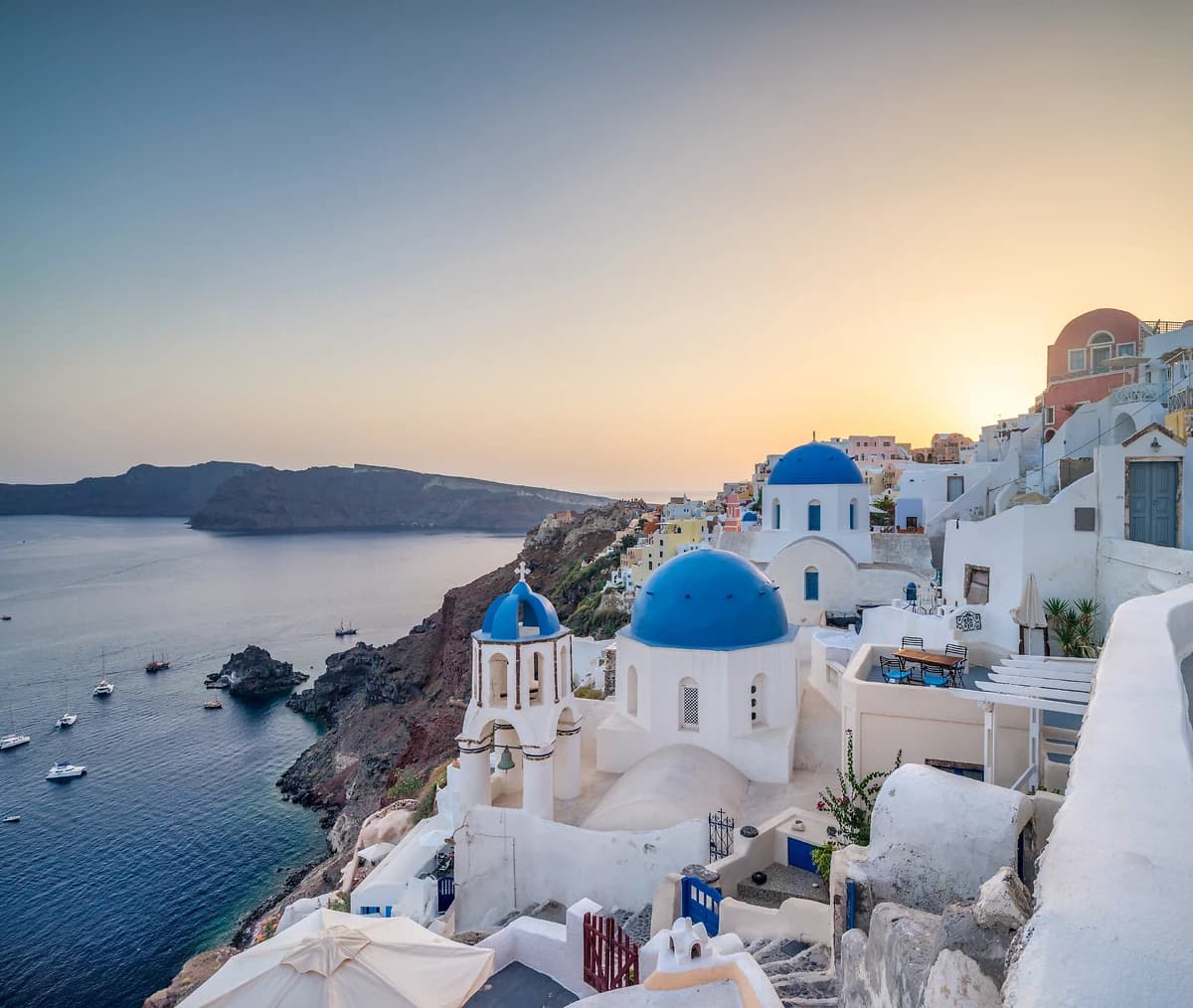 Vue au coucher du soleil de l'église au dôme bleu à Oia, Santorin, Grèce